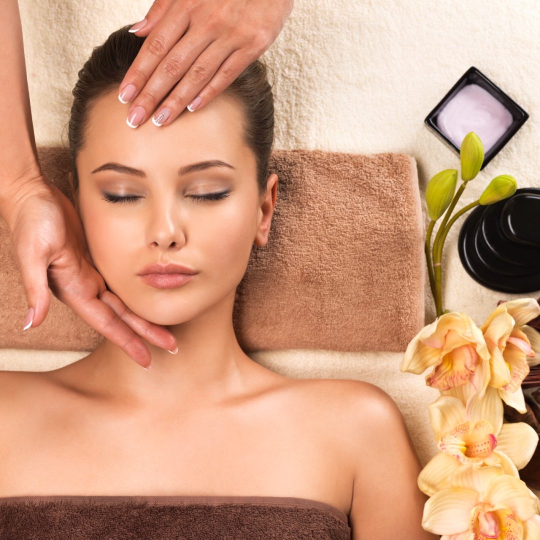 Portrait of beautiful young woman relaxing with head massage at spa salon.
